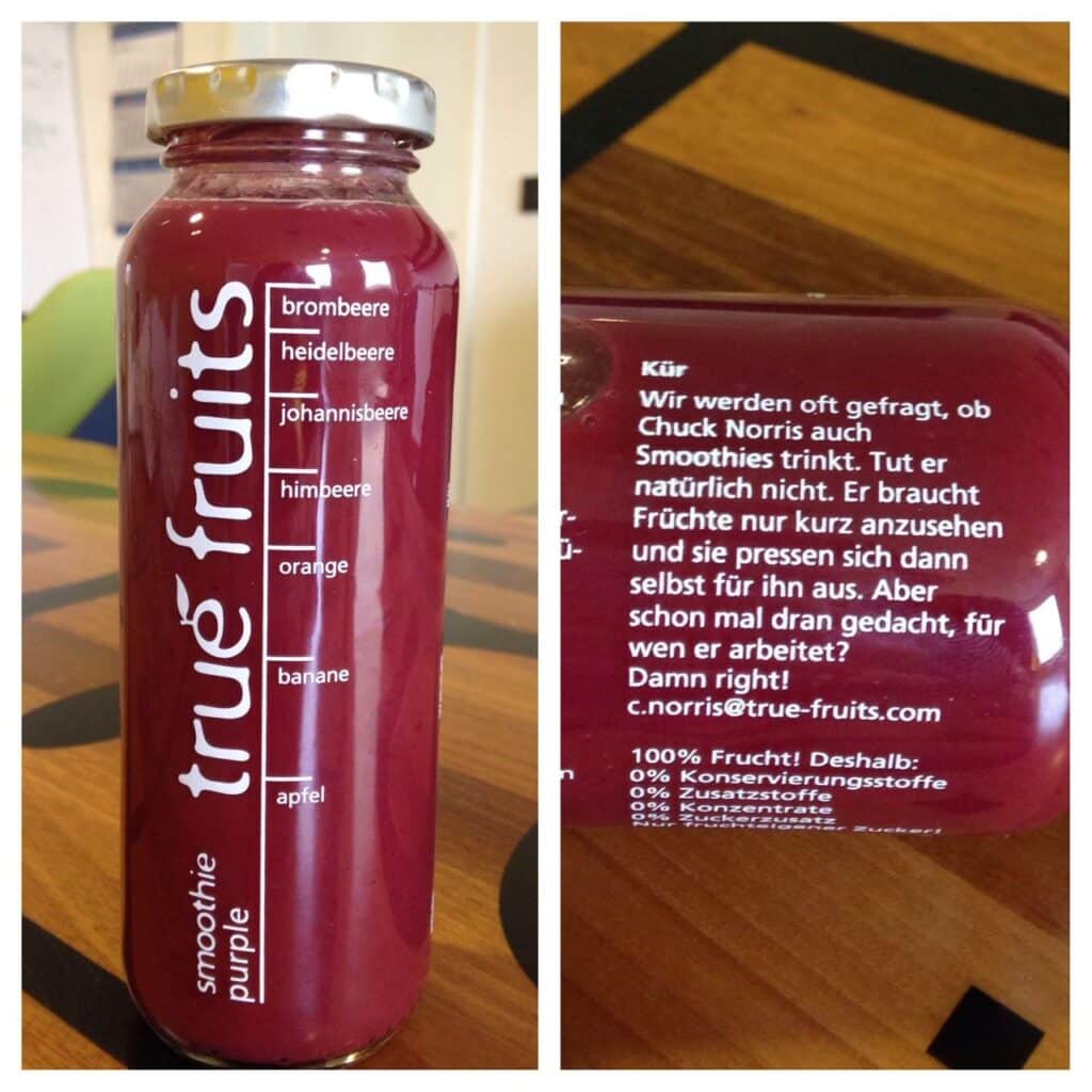 Gauche : Une bouteille de smoothie True Fruits au contenu rouge est posée sur une table en bois. L'avant affiche la liste des ingrédients en lettres blanches, comprenant mûre, myrtille, cassis, framboise, orange, banane et pomme. Le logo « true fruits » est imprimé verticalement sur la bouteille. Droite : Le dos de la bouteille présente un texte humoristique en blanc sur Chuck Norris. Le texte explique que Chuck Norris ne boit pas de smoothies, car les fruits se pressent d’eux-mêmes lorsqu’il les regarde, et demande pour qui il travaille, avec la réponse : « Damn right! c.norris@true-fruits.com ». En dessous, il est écrit : « 100 % fruit ! Donc : 0 % conservateurs ».